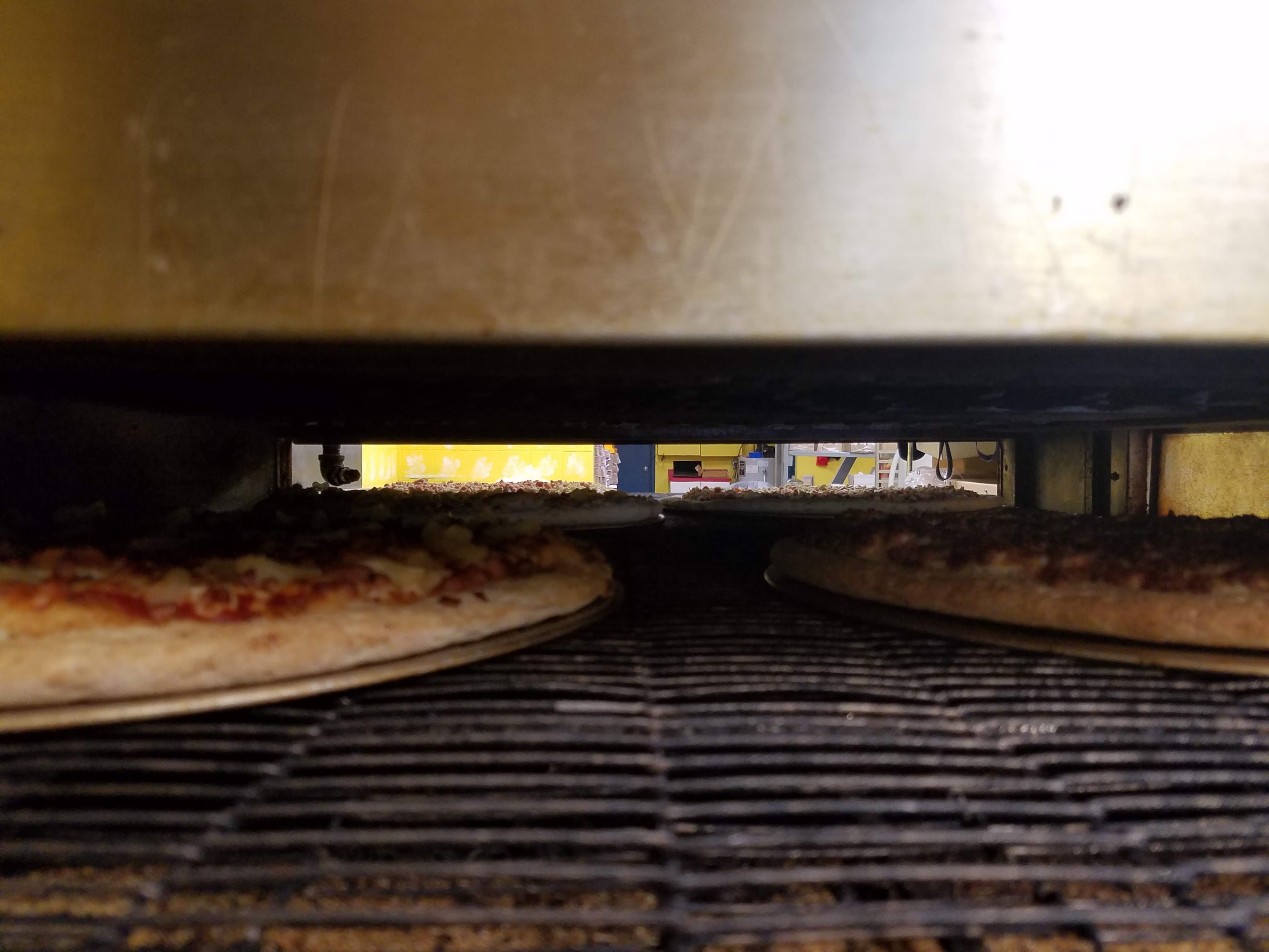 Pizzas going through the oven at Gino's